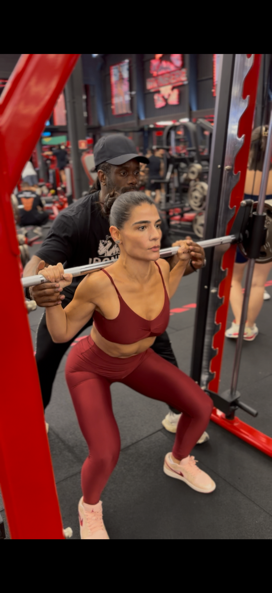 Dra Camila Pereira praticando agachamento com supervisão profissional